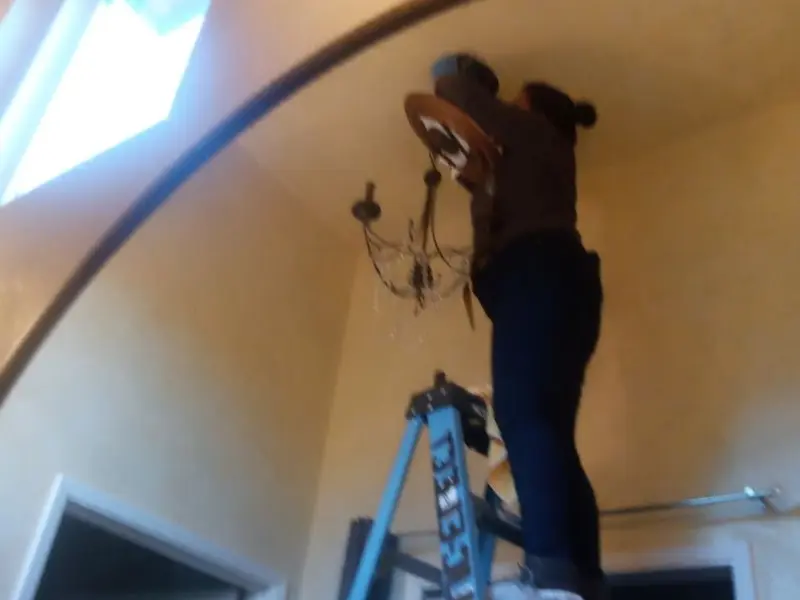 Electrician installing a chandelier in a Denver City residence